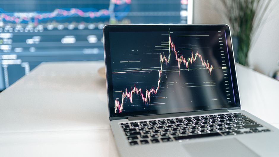 A laptop screen showing cryptocurrency market data beside a keyboard